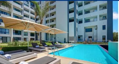 a swimming pool with chairs and umbrellas next to a building at Luxurious 2 bedroom @ The Regency Hotel in Pretoria