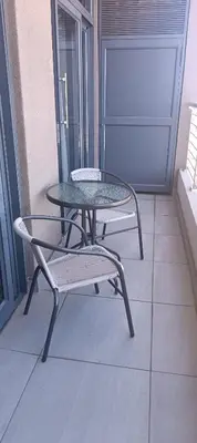 a table and a chair on a balcony at Menlyn Maine Trilogy Apartment 1215 in Pretoria