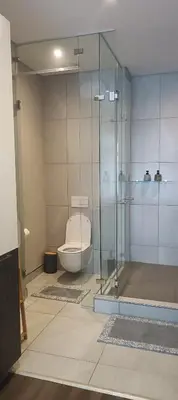 a bathroom with a toilet and a glass shower at Menlyn Maine Trilogy Apartment 1215 in Pretoria