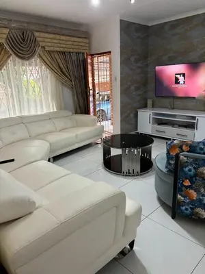 a living room with white furniture and a flat screen tv at Blissful stay in Polokwane