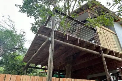 a tree house with a deck on top of a fence at Tree Symphony in Marloth Park