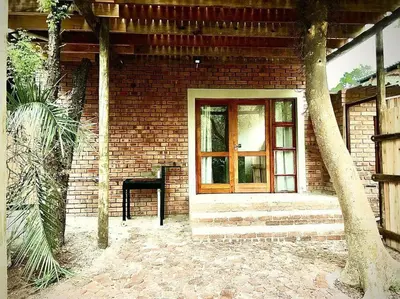 a brick house with a window and a chair at Tree Symphony in Marloth Park