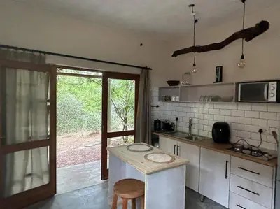 a kitchen with a counter and a table in it at Tree Symphony in Marloth Park