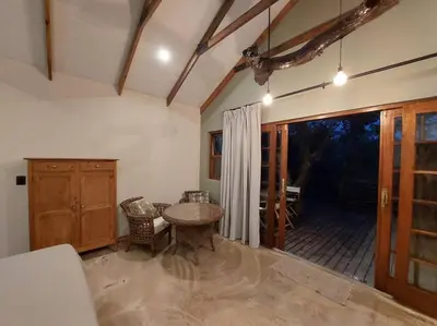 a living room with a table and a patio at Tree Symphony in Marloth Park