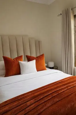 a bedroom with a large bed with orange and white pillows at Midrand Chic Oasis in Midrand