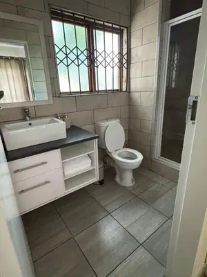 a bathroom with a toilet and a sink and a mirror at Midrand Chic Oasis in Midrand
