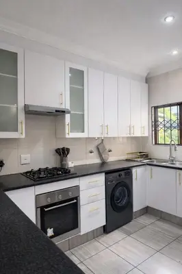 a kitchen with white cabinets and a black dishwasher at Midrand Chic Oasis in Midrand