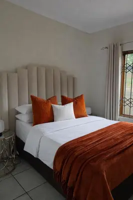 a bedroom with a large white bed with orange pillows at Midrand Chic Oasis in Midrand