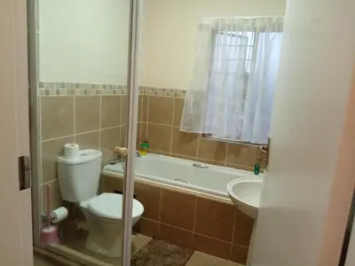 a bathroom with a toilet and a tub and a sink at Alternate Cosy Home in Pretoria