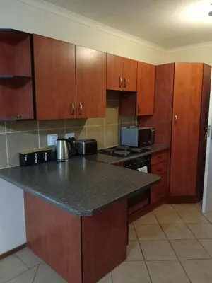 a kitchen with a granite counter top and wooden cabinets at Alternate Cosy Home in Pretoria