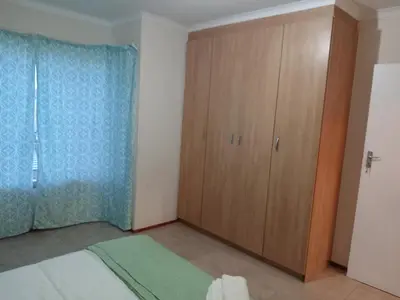 a bedroom with a wooden cabinet in a room at Alternate Cosy Home in Pretoria