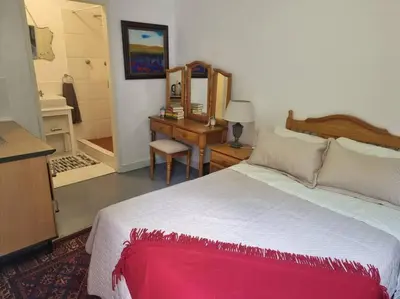 a bedroom with a large bed and a desk at Cottage by the Woods in Pretoria