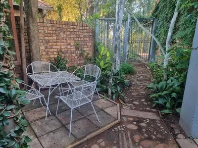 a patio with a table and chairs and a fence at Cottage by the Woods in Pretoria