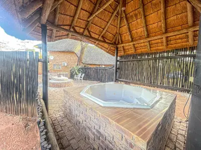 an outdoor bath tub in a building with a wooden roof at Walking Tall Private Bush Retreat in Marloth Park