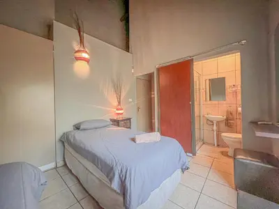 a bedroom with a bed and a bathroom with a toilet at Walking Tall Private Bush Retreat in Marloth Park