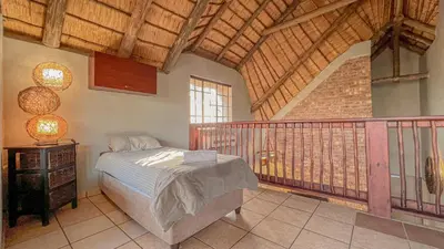 a bedroom with a bed and a balcony at Walking Tall Private Bush Retreat in Marloth Park