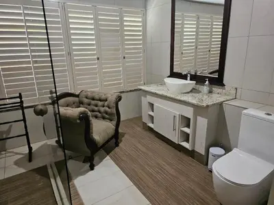 a bathroom with a chair and a sink and a toilet at Arum Lily Eloff in Delmas