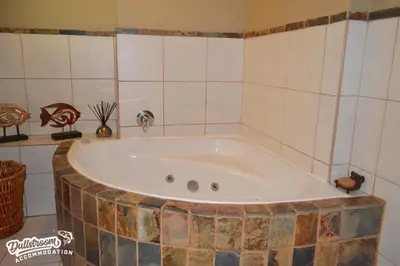 a bath tub in a bathroom with a tiled wall at Forest Vista in Dullstroom