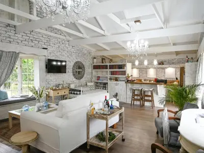 a living room with white furniture and a stone wall at Rose and Ivy Cottages in Louis Trichardt