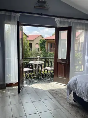 a bedroom with a door open to a patio with a table at Dullies Dolce in Dullstroom