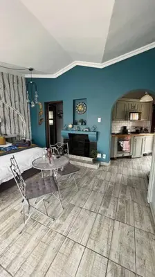 a living room with blue walls and a table and a bed at Dullies Dolce in Dullstroom