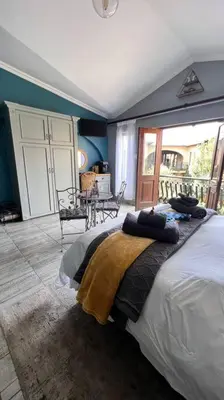 a bedroom with a bed in a room with a balcony at Dullies Dolce in Dullstroom