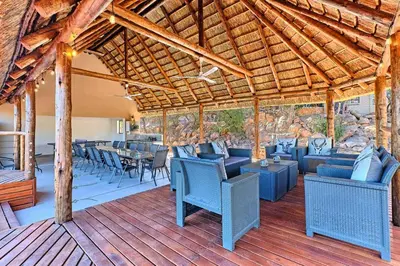 a patio with blue chairs and tables on a wooden deck at Thula-Thula Private Game Lodge Mabalingwe in Bela-Bela