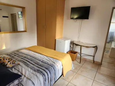 a bedroom with a bed and a table and a television at View on 83 in Tzaneen