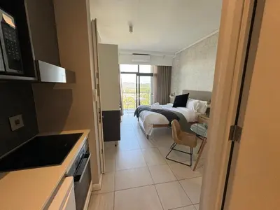 a bedroom with a bed and a table and a chair at Menlyn Maine Triology - 10 On Capital in Pretoria