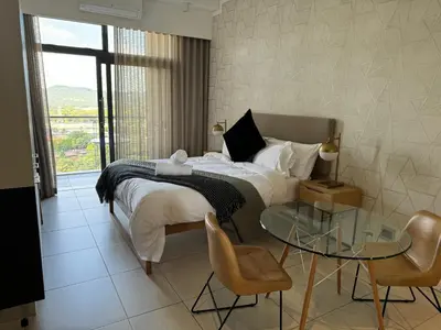 a bedroom with a bed and a glass table and chairs at Menlyn Maine Triology - 10 On Capital in Pretoria