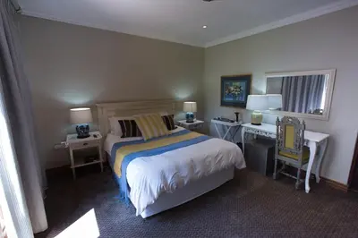a bedroom with a bed and a desk and a desk at MacGregors Guest House in Pretoria