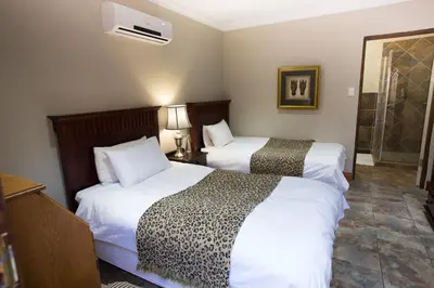 a hotel room with two beds and a shower at MacGregors Guest House in Pretoria