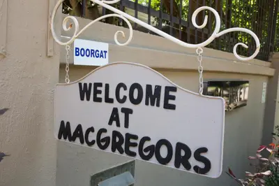 a sign that says welcome at macrocopes hanging on a building at MacGregors Guest House in Pretoria