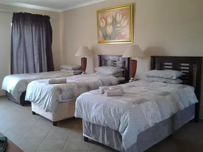 a hotel room with two beds in a room at Airport Lodge Guest House in Kempton Park