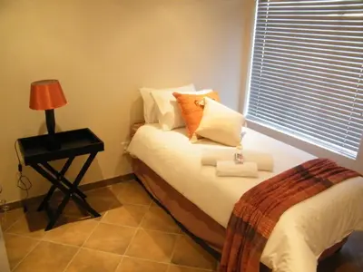 a small bedroom with a bed and a lamp on a table at Airport Lodge Guest House in Kempton Park
