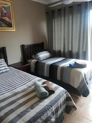 two beds sitting next to each other in a room at Airport Lodge Guest House in Kempton Park