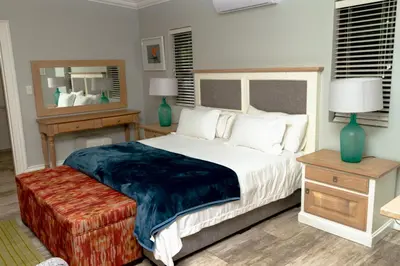 a bedroom with a large bed and a mirror at The Good Host in Waterval-Onder