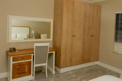 a bedroom with a desk and a mirror at The Good Host in Waterval-Onder