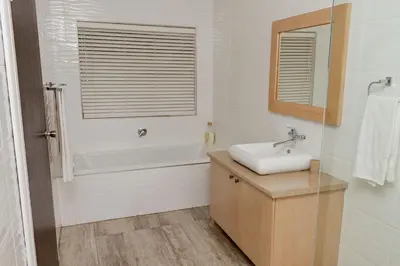 a white bathroom with a sink and a bath tub at The Good Host in Waterval-Onder