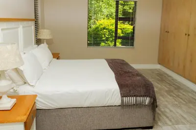 a bedroom with a bed and a desk and a window at The Good Host in Waterval-Onder