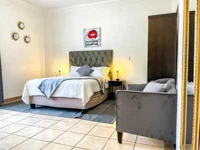 a bedroom with a large bed and a chair at Bobisemo Luxury Guesthouse in Pretoria