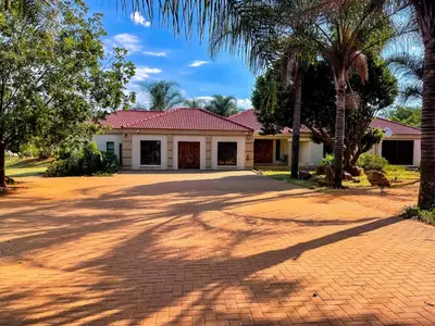 a house with palm trees and a brick driveway at Bobisemo Luxury Guesthouse in Pretoria