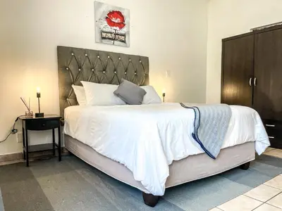 a bedroom with a large white bed and a table at Bobisemo Luxury Guesthouse in Pretoria
