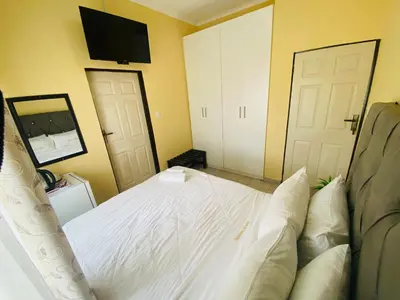a bedroom with a white bed with a tv on the wall at Lalamnandzi 4 in White River