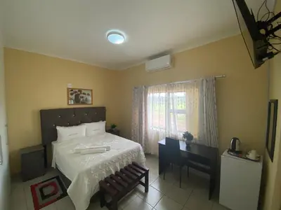 a bedroom with a bed and a desk and a window at Lalamnandzi 4 in White River
