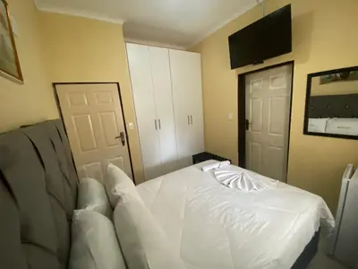 a bedroom with a white bed and a flat screen tv at Lalamnandzi 4 in White River