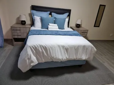 a bedroom with a large bed with blue pillows at Lasev guesthouse in Pretoria