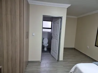 a bathroom with a toilet and a door to a room at Lasev guesthouse in Pretoria