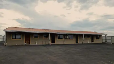 a small building with a fence in a parking lot at Lasev guesthouse in Pretoria