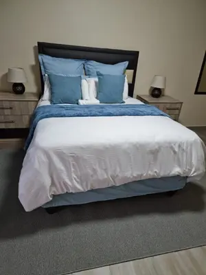 a bedroom with a large bed with blue pillows at Lasev guesthouse in Pretoria